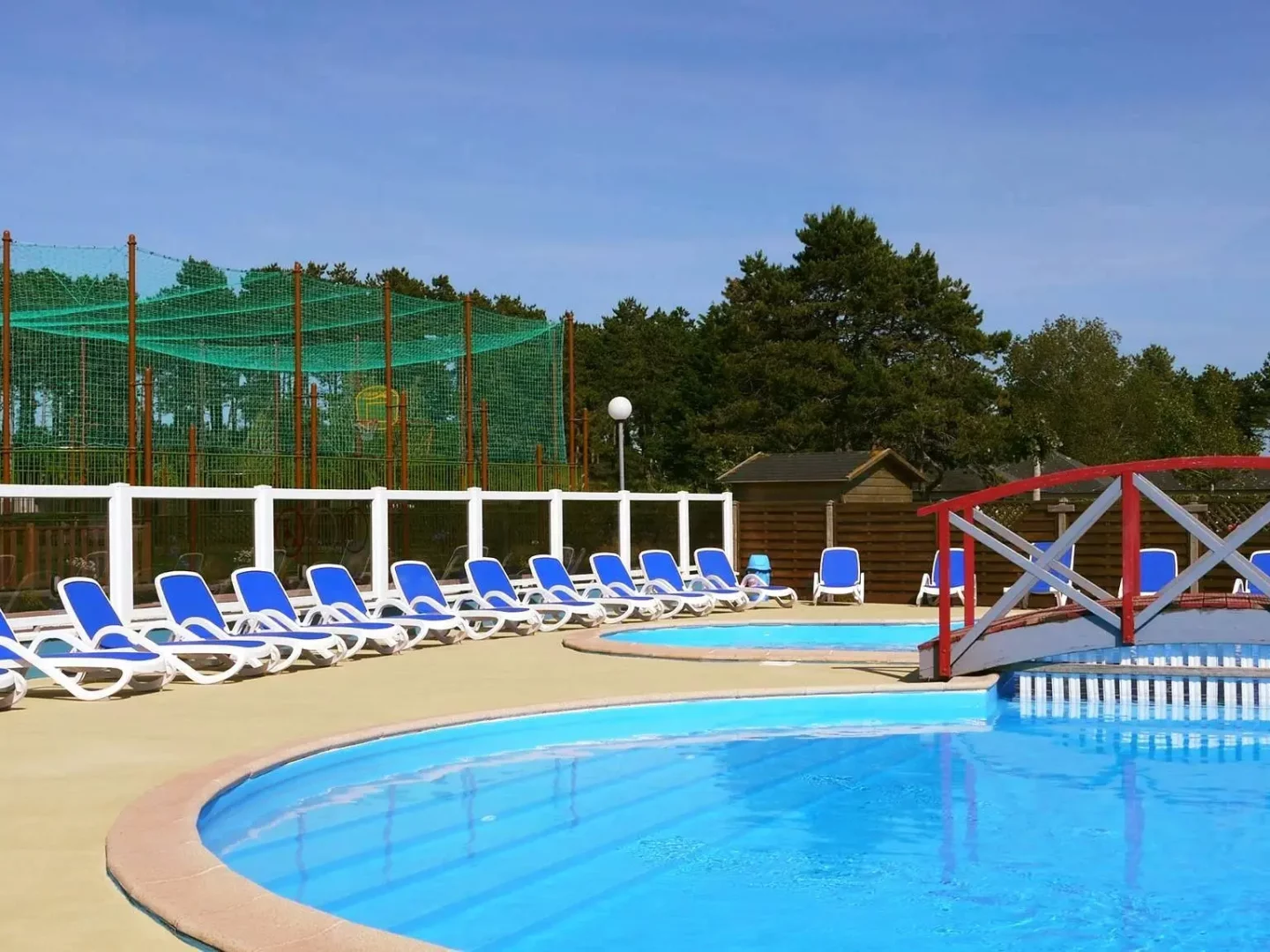 la piscine chauffée du camping Les Bosquets et la terrasse avec transats